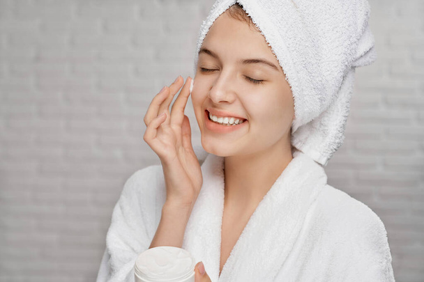 Young woman applying on face cream for hydrating of skin. - Foto, Bild