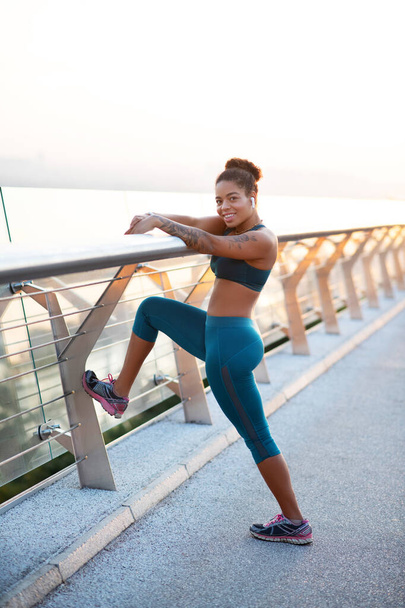 Cheerful dark-skinned woman stretching her body after run - Photo, Image