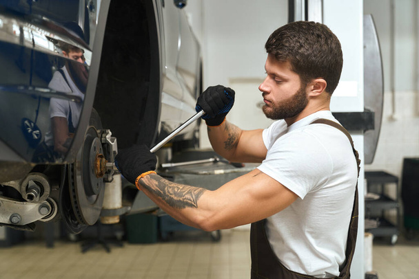 View from side of handsome man changing tire of car - Foto, Imagem