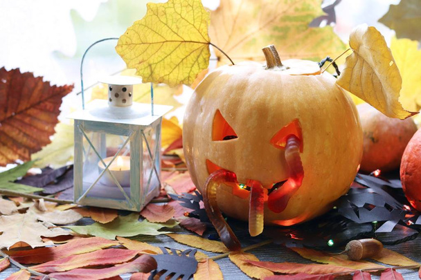 Halloween-Komposition aus Buchse-o-Laterne, Kürbissen, Lampen, Illuminationen, mystischem Dekor auf dem Hintergrund eines Fensters und Herbstblättern, saisonalen Feiertagen - Foto, Bild