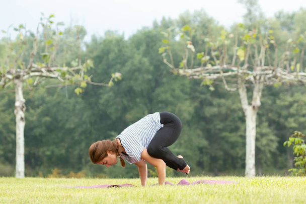 Young beautiful woman doing yoga exercise in green park. Healthy lifestyle and fitness concept. - Φωτογραφία, εικόνα