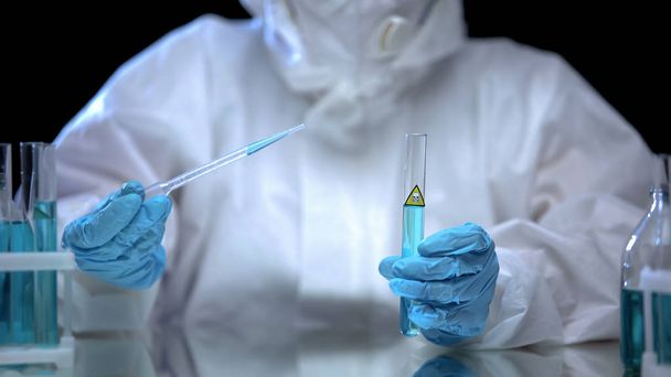 Person in protective suit taking sample with poison from test-tube, researches - Fotó, kép