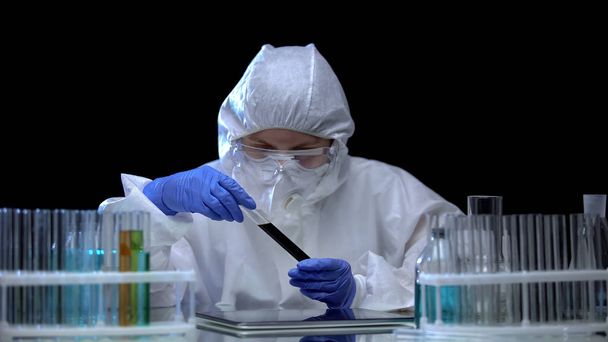 Laboratory scientist studying black liquid in tube, dangerous substance, safety - Valokuva, kuva