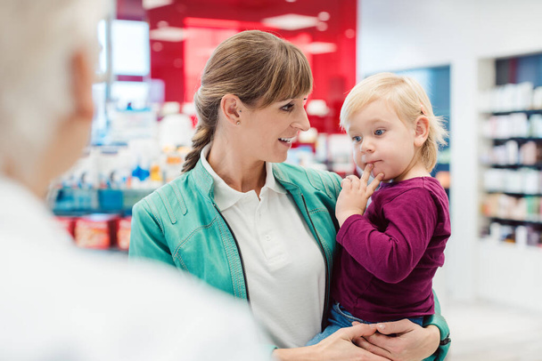 Mother with daughter in pharmacy at the counter - Foto, afbeelding
