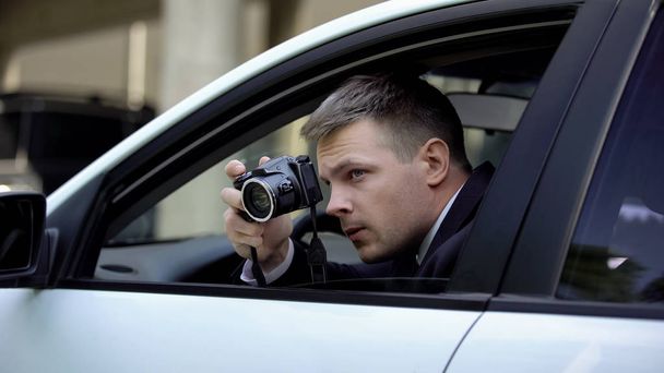 Male agent secretly taking photo by camera sitting in car, photojournalism - Fotoğraf, Görsel