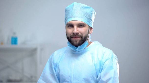 Happy surgeon in medical face mask smiling after successful operation, work - Foto, immagini