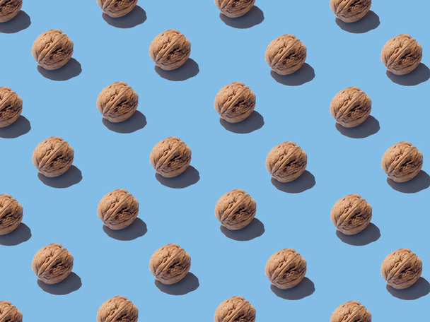 Creative pattern of walnuts on a bright blue background. - Foto, afbeelding