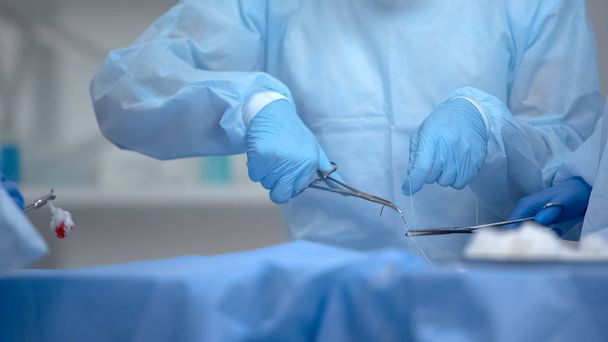 Professional surgeons sewing patient after hospital operation, healthcare - Φωτογραφία, εικόνα