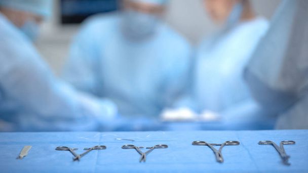 Equipamento médico estéril deitado na mesa, cirurgiões realizando operação, saúde
 - Foto, Imagem