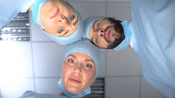 Serious surgeon team faces looking at patient waking up after coma, monitoring - Foto, imagen