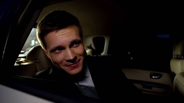 Handsome actor looking at public from car backseat, enjoying movie premier party - Фото, изображение