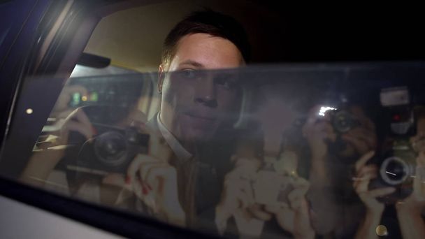 Famous male superstar closing car window, hiding from paparazzi cameras, scandal - Фото, зображення