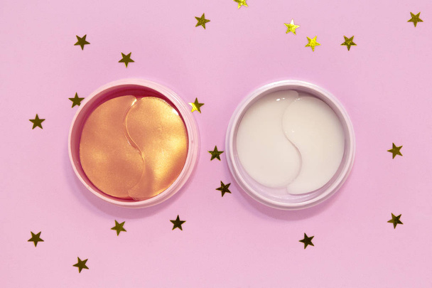 Two cans hydrogel cosmetic eye patch for skin care on pink background with golden stars. Flat lay, top view. - Photo, Image