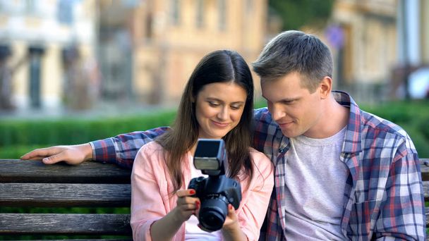Couple watching photos from walk on professional camera, spending leisure time - 写真・画像