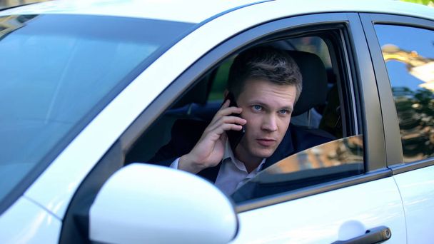 Człowiek siedzi w samochodzie, szpiegostwo żona z kochankiem, rozmowa telefoniczna z wynajętym zabójcą - Zdjęcie, obraz