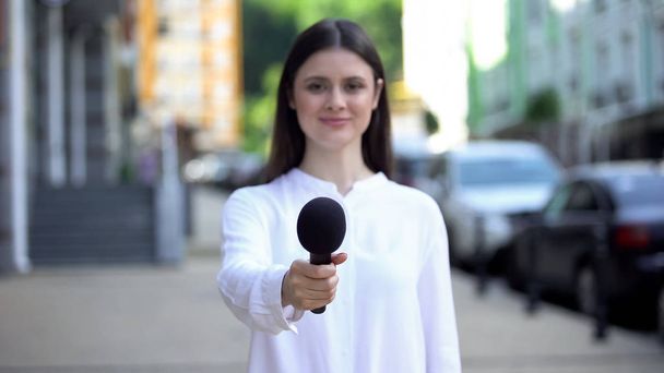 Female reporter proposing microphone, taking interview on street, daily news - Valokuva, kuva