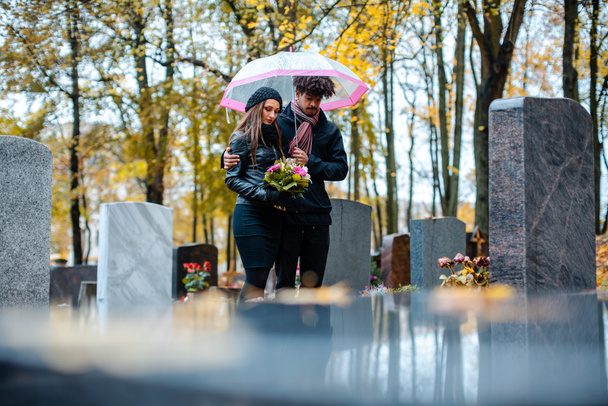 Pareja de luto por un ser querido fallecido en el cementerio en otoño
 - Foto, Imagen