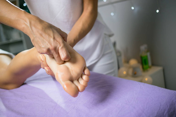Female relaxing foot massage with hands. Beauty body skin care treatment concept. - 写真・画像