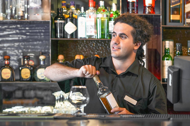 Barista maschio dà un bicchiere di whisky
 - Foto, immagini