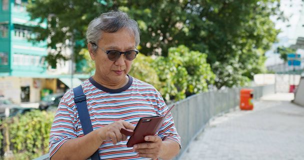 アジアの老人が市内でスマートフォンを使う - 写真・画像