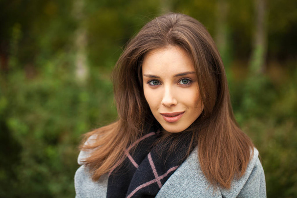 Young brunette woman in a gray coat with a fur collar  - Фото, зображення