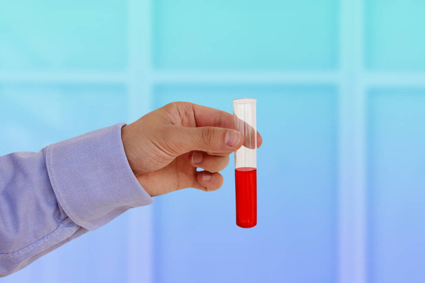 mannelijke hand met bloed in een reageerbuis, concept bloeddonatie, close-up - Foto, afbeelding