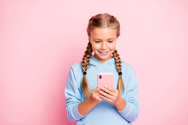 Photo of pretty little lady holding telephone hands reading positive comments for new post wear casual blue hoodie pullover isolated pastel pink color background - 写真・画像