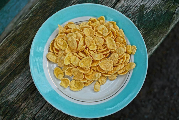 fiocchi di mais secchi gialli in un piatto su un tavolo grigio
 - Foto, immagini
