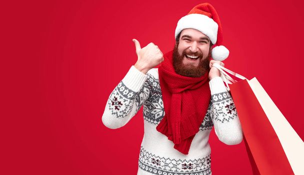 Man with Christmas purchases pointing aside - Photo, Image