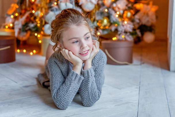 Kislány ajándékdobozzal közel karácsonyfa otthon - Fotó, kép