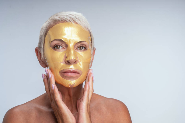 Serious blonde woman doing procedures for her face - Фото, зображення