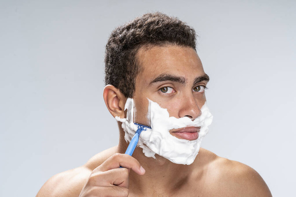 Calm young man shaving in the morning - Фото, изображение