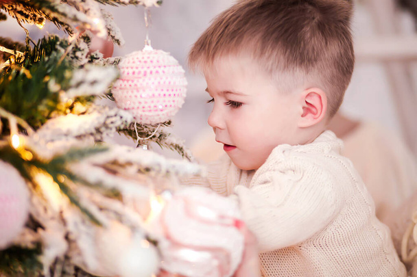 Pequeño niño lindo decora un árbol de Navidad
 - Foto, Imagen