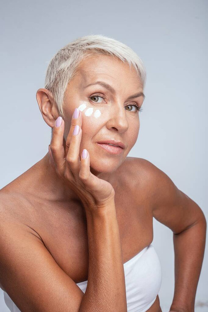 Cheerful senior female person testing face foundation - Foto, Imagem