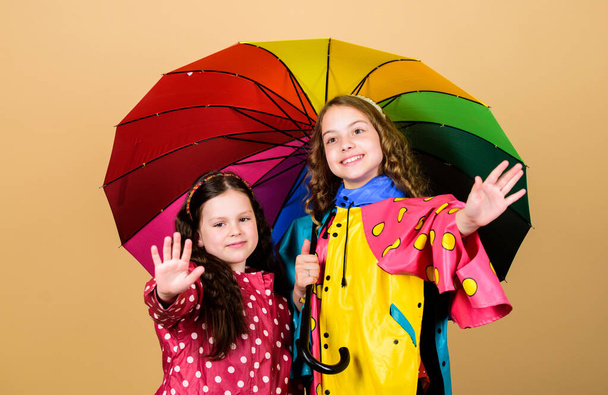 happy little girls with colorful umbrella. autumn fashion. cheerful hipster children, sisterhood. rain protection. Rainbow. family bonds. Little girls in raincoat. Fresh air and good mood - Foto, afbeelding