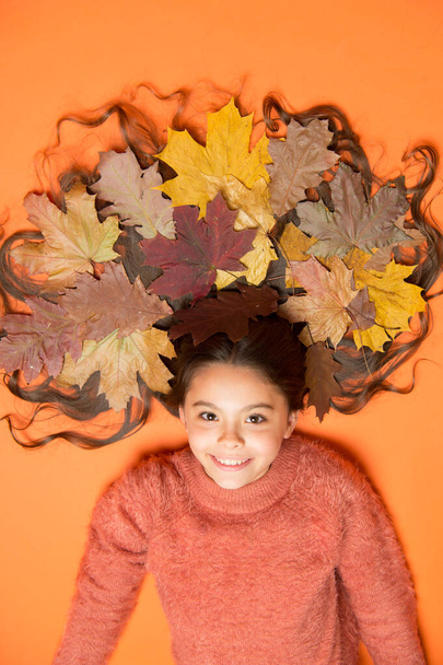 Autumn leaves are falling down. Happy girl wear colorful leaves in long hair. Creating hairstyle using fall leaves. Having fun with fallen leaves. Hair beauty salon. Hairdressing - Φωτογραφία, εικόνα