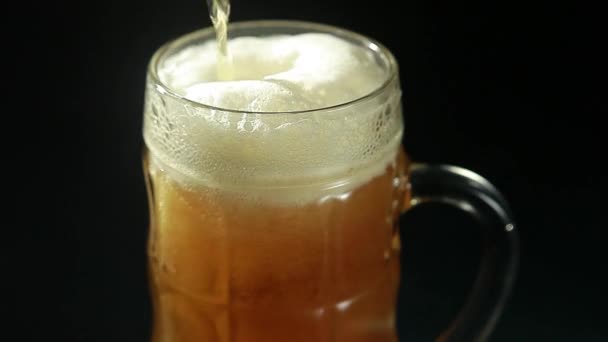 La cerveza se vierte en un vaso sobre un fondo negro de cerca
 - Imágenes, Vídeo