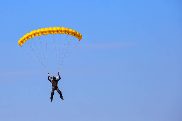 Fallschirmspringer mit gelbem Fallschirm in blauem Himmel - Foto, Bild