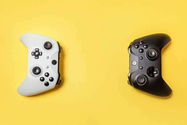 Fehér és fekete két joystick sárga háttéren. Számítógépes játék verseny videogame kontroll konfrontáció koncepció - Fotó, kép