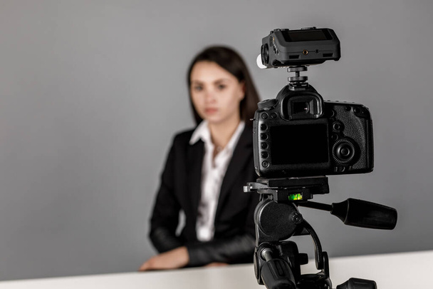 A woman makes a video for her blog using a tripod mounted digita - 写真・画像