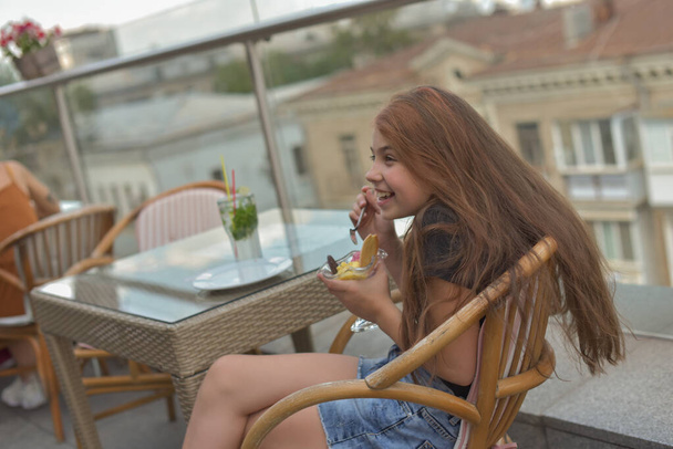 Belle jeune femme souriante heureuse, regardant la caméra assise dans un restaurant ou un café et mangeant de la crème glacée
 - Photo, image