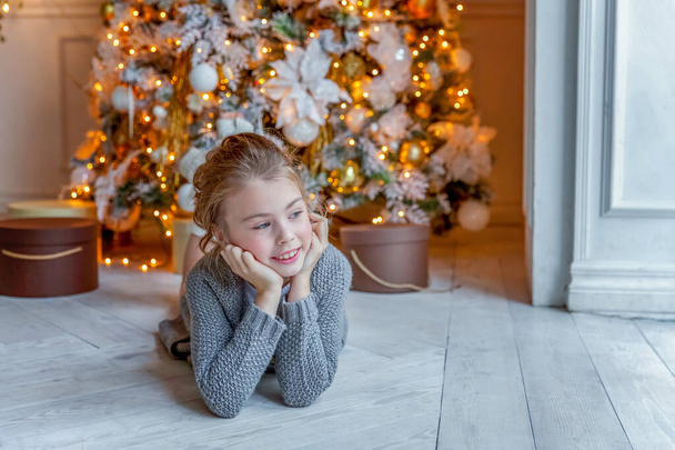 Little girl with gift box near Christmas tree at home - Foto, Imagen