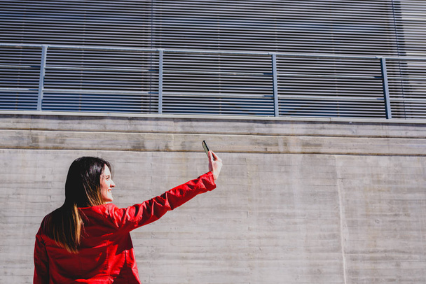 Milenial mujer tomando una selfie con gesto feliz para fingir
 - Foto, imagen