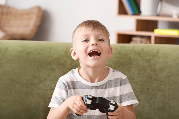 Emotionele kleine jongen spelen videospelletjes thuis - Foto, afbeelding