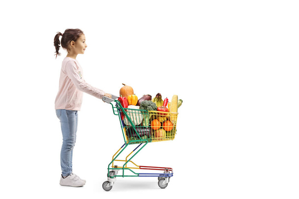 Little girl buying fruits and vegetables in a mini shopping cart - Foto, imagen