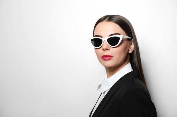 Young businesswoman in stylish sunglasses on light background, space for text - Fotoğraf, Görsel