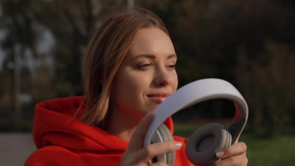 European woman puts on headphones enjoy listening to music - Filmmaterial, Video