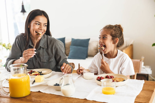 Image of beautiful family mother and little daughter eating toge - Foto, imagen