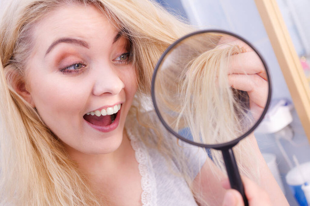 Woman looking at hair ends through magnifying glass - Foto, Imagem