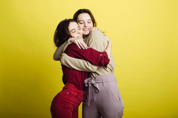 Image of happy young girls standing isolated over yellow background. Girls - Fotografie, Obrázek